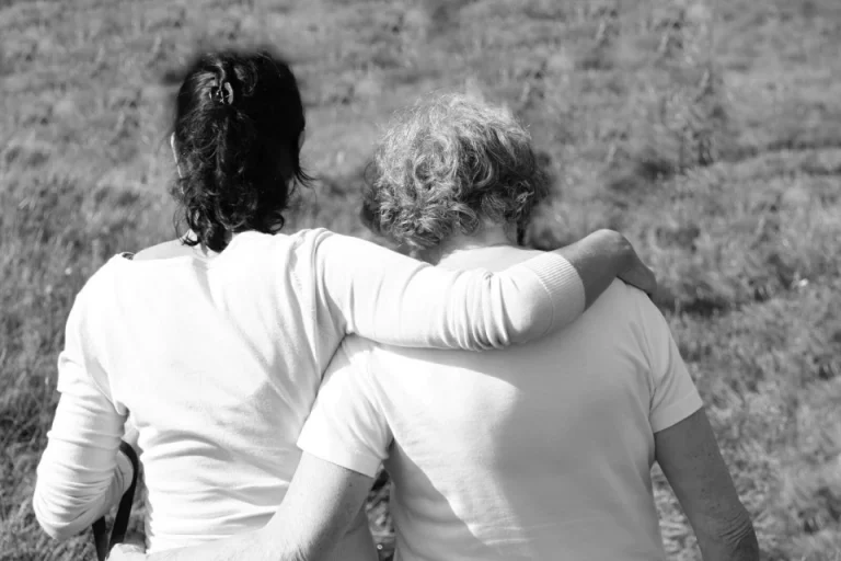 Black and white photo of two people walking in a field near a tattoo shop.