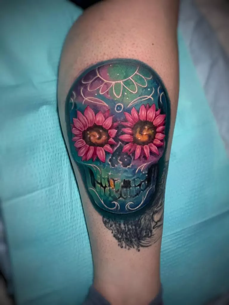 A woman's leg adorned with a vibrant sugar skull tattoo in Katy.