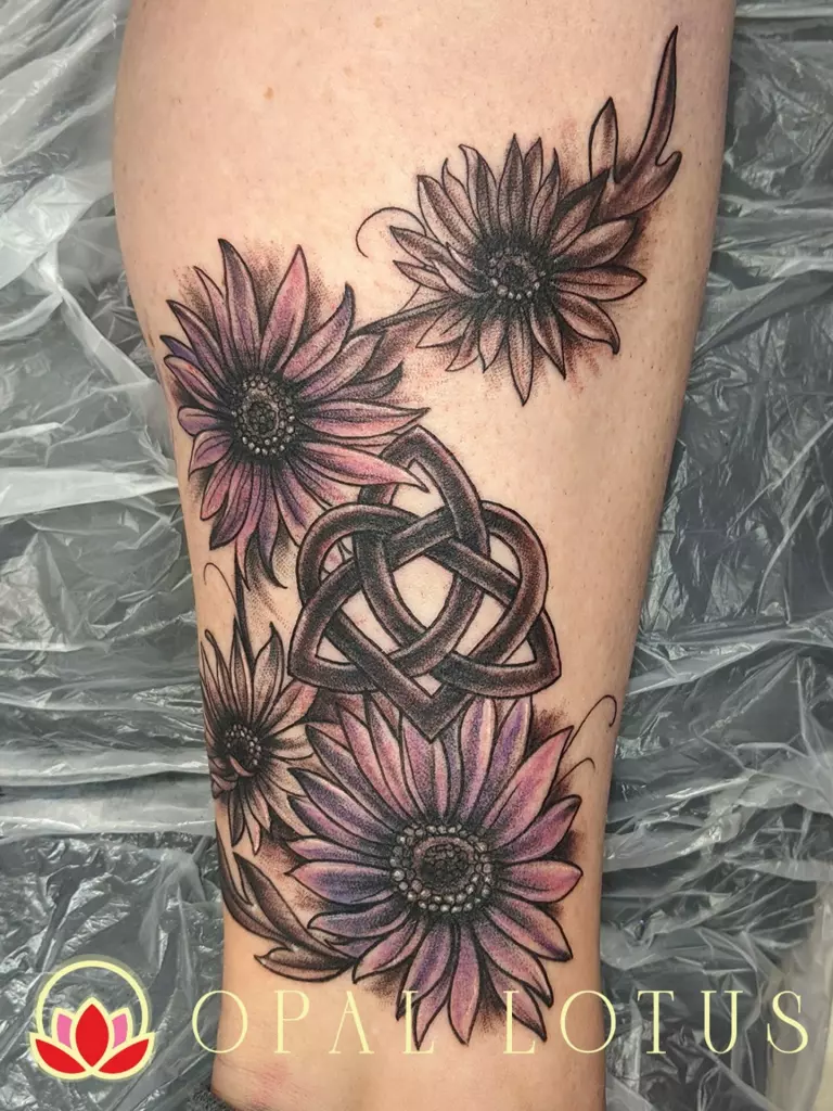 A floral tattoo featuring a celtic knot on the thigh.