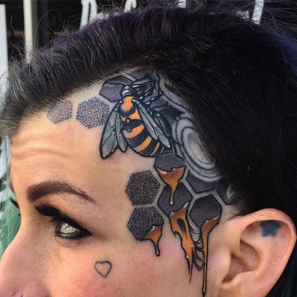 A woman with a new school blackwork bee tattoo on her head, done by Mikey.