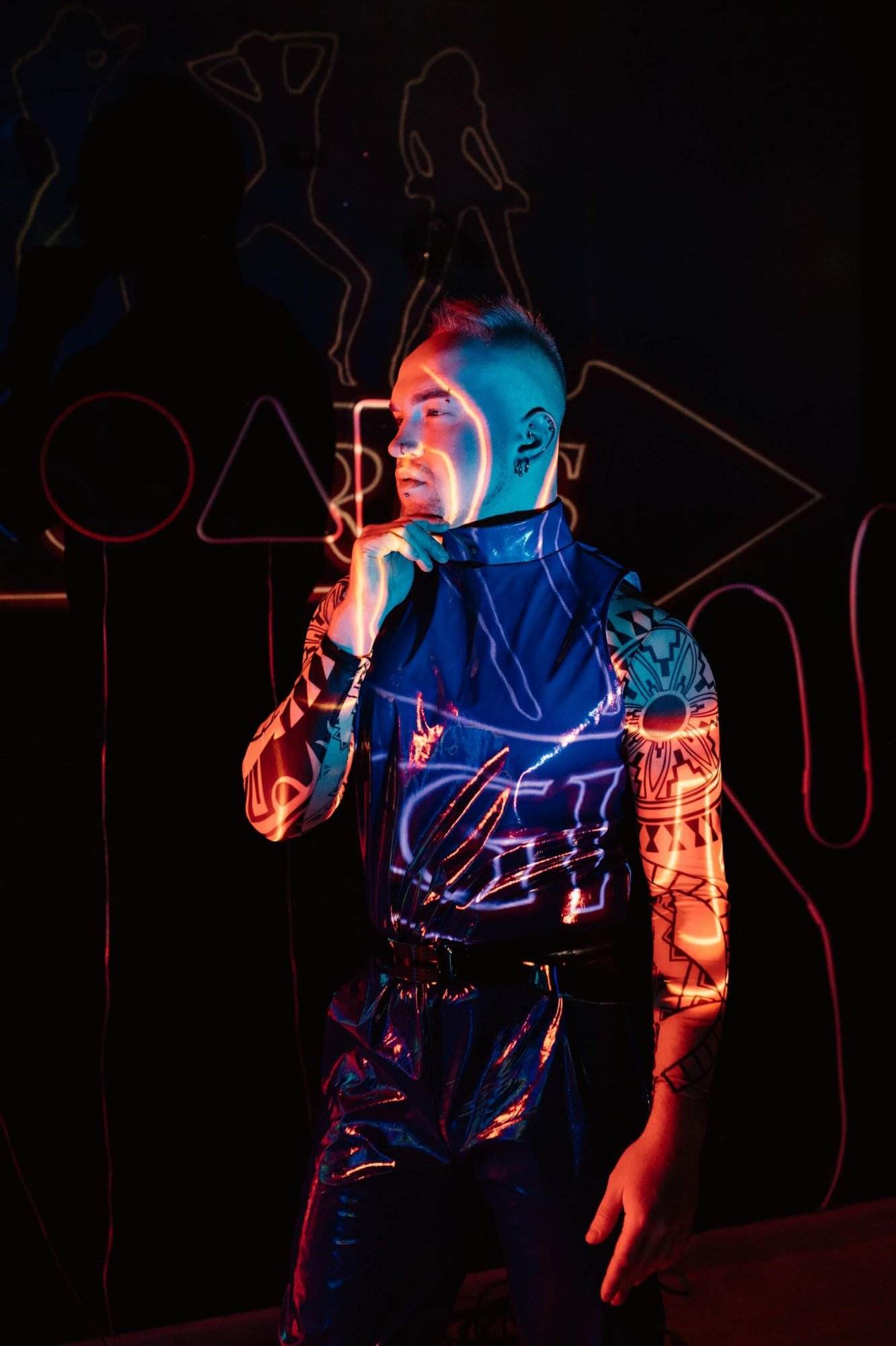 A person in striking cyberpunk attire illuminated by vibrant neon lights.