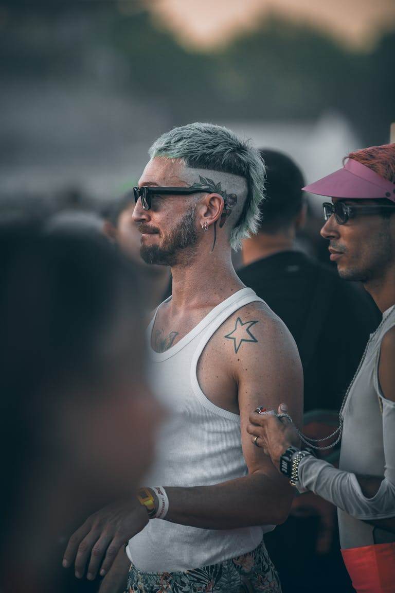 Man with sunglasses and star tattoo at an outdoor music festival.